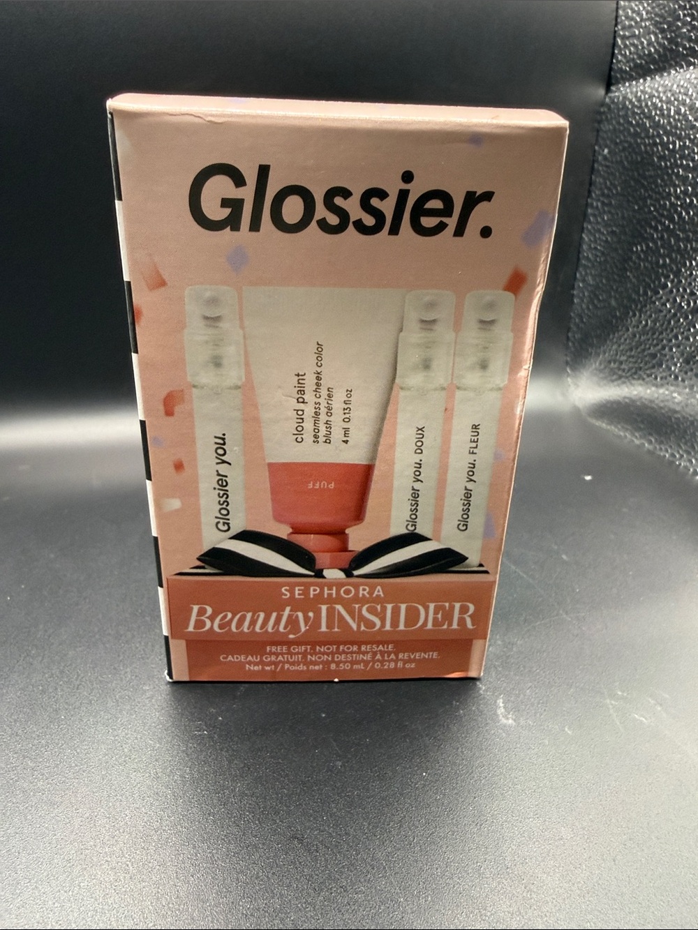 Glossier mini Cloud Paint blush in Puff alongside three mini fragrance samples